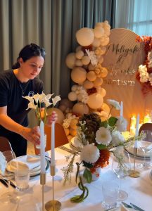 Event stylist placing floral arrangement on a table during baptism event setup by Colourful Treasures
