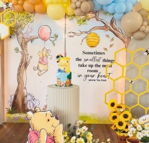 Winnie the Pooh Hundred Acre Wood birthday styling featuring custom book prop, character props and themed balloon garland by Colourful Treasures