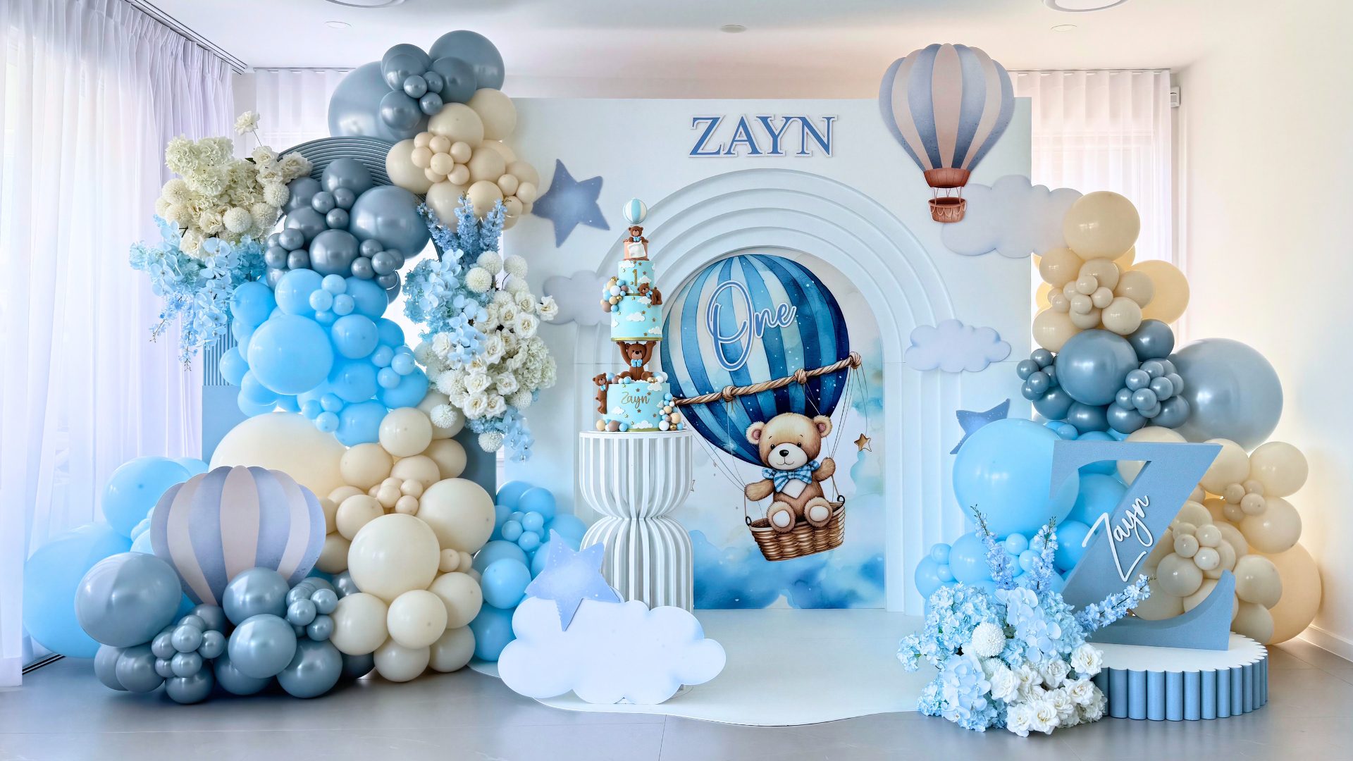 teddy toile hot air balloon birthday styling with grand 3d arch hourglass cake stand blue and white pastel balloon garland and lush florals by Colourful Treasures